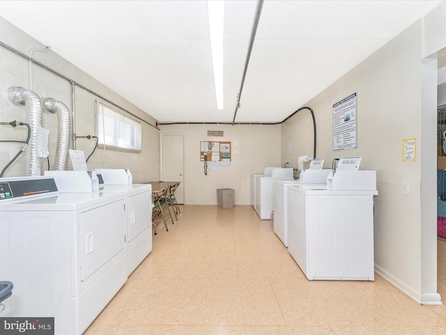 common laundry area with washing machine and dryer, baseboards, and light floors