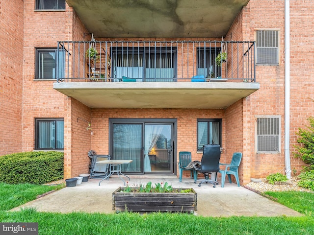 rear view of property featuring a patio area, brick siding, and a balcony