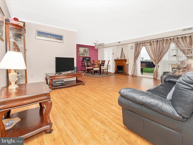 living area featuring a fireplace, visible vents, ornamental molding, and wood finished floors