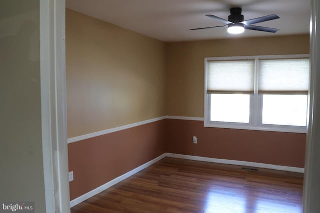 spare room featuring wood finished floors, visible vents, a ceiling fan, and baseboards