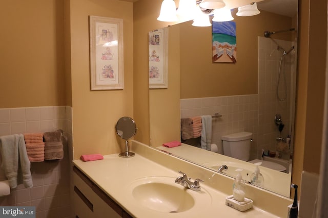 full bathroom with wainscoting, vanity, tile walls, shower / washtub combination, and toilet