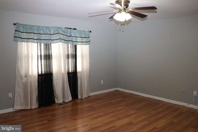 spare room featuring baseboards, wood finished floors, and ceiling fan