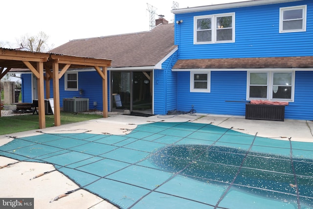 back of property with a patio area, a covered pool, and central air condition unit