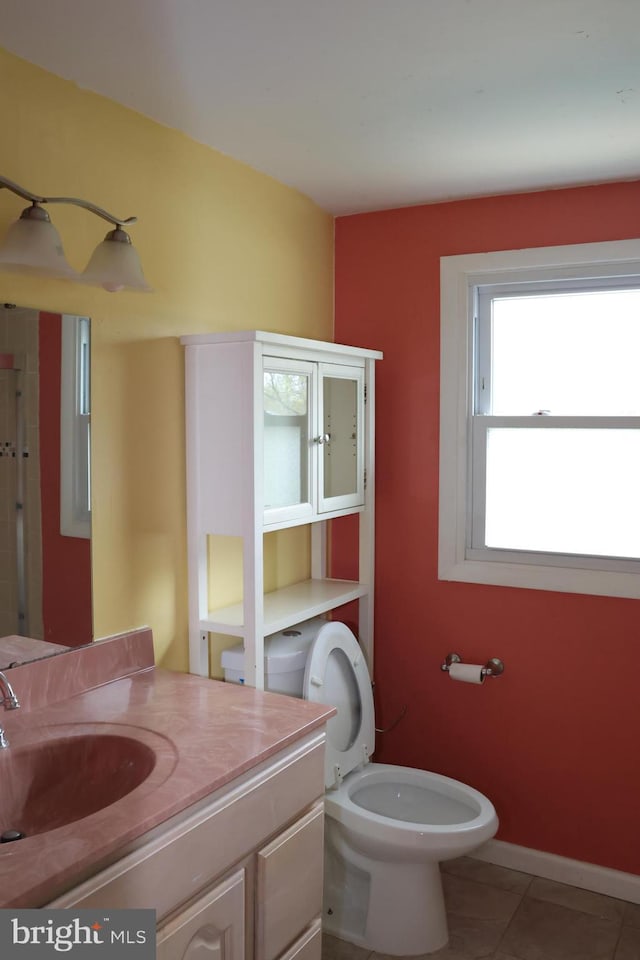 bathroom with toilet, vanity, tile patterned floors, and baseboards