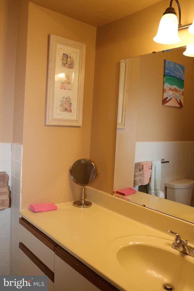 bathroom with toilet, vanity, and tile walls
