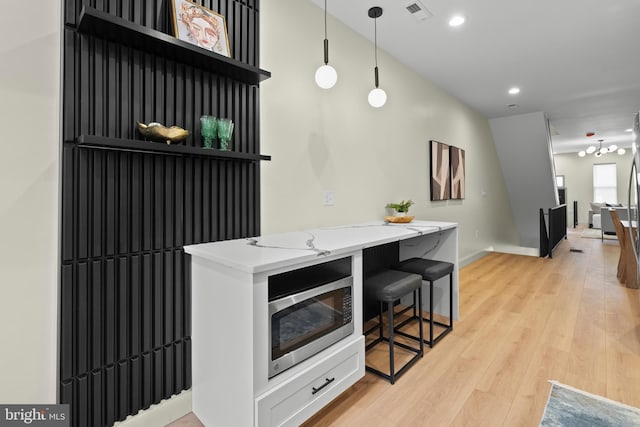 325 Gilmor St, Baltimore, MD 21223 - kitchen with light stone counters, open shelves, visible vents, stainless steel microwave, and pendant lighting