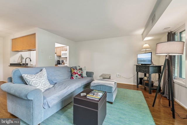 living room with visible vents, baseboards, and wood finished floors
