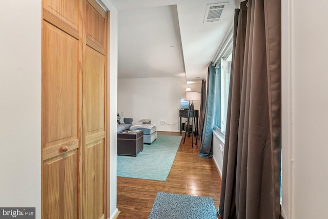 hall featuring baseboards, visible vents, and wood finished floors