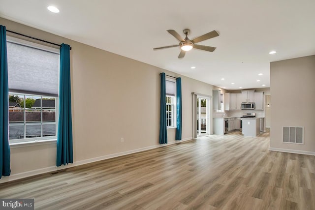 unfurnished living room with light wood finished floors, visible vents, baseboards, and ceiling fan