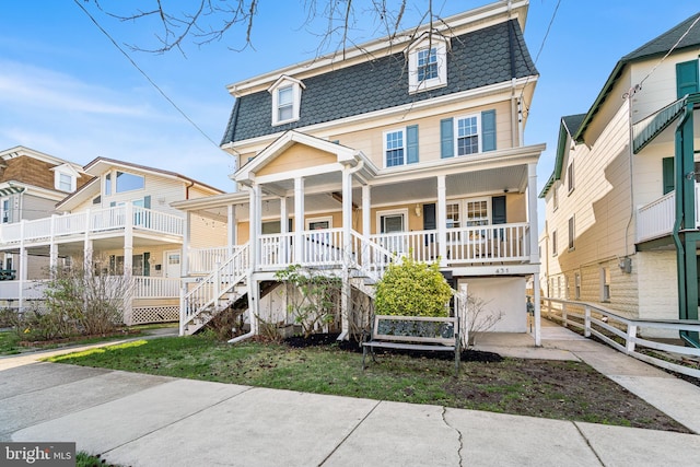 second empire-style home with stairway, fence, mansard roof, and covered porch