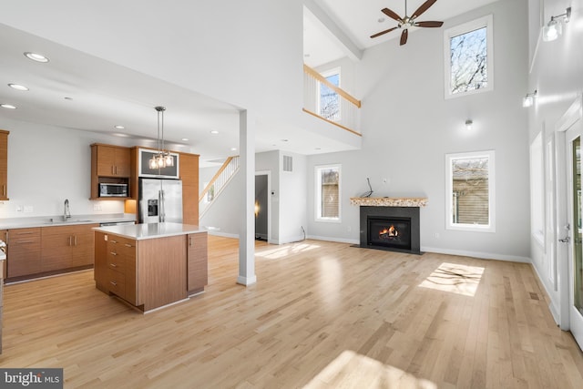 kitchen featuring light wood-style flooring, a center island, a sink, stainless steel appliances, and brown cabinets