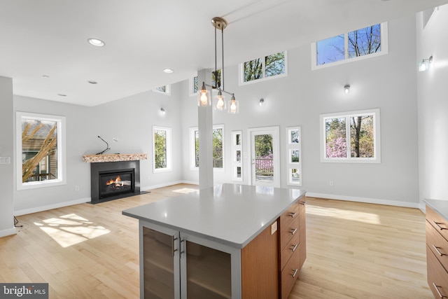 kitchen with baseboards, open floor plan, light wood-type flooring, recessed lighting, and a fireplace with flush hearth