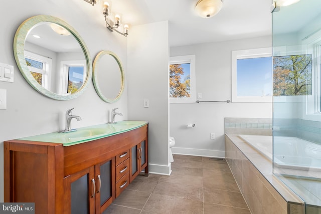full bath with tiled tub, toilet, a sink, double vanity, and baseboards