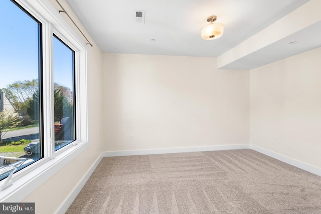 spare room with carpet flooring, visible vents, and baseboards