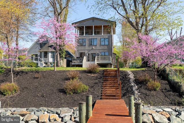 rear view of property featuring stairs and fence