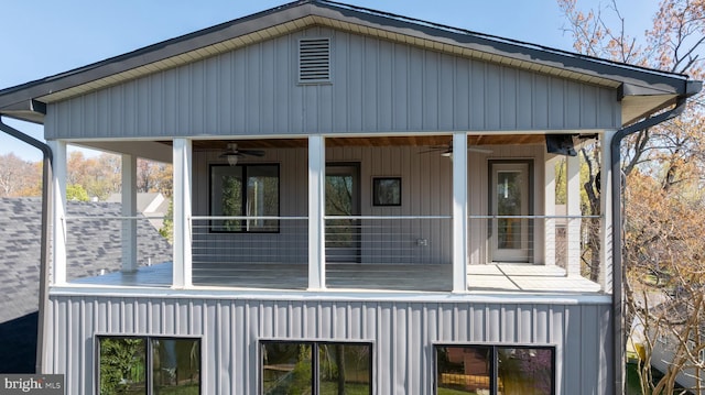 view of side of property with board and batten siding, a ceiling fan, and a sunroom