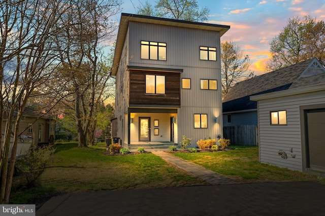 view of front of property with a porch, fence, and a lawn