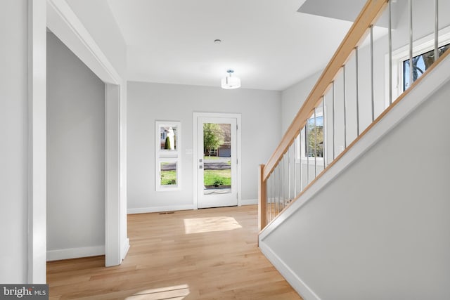 foyer entrance featuring light wood-style floors, baseboards, and stairs
