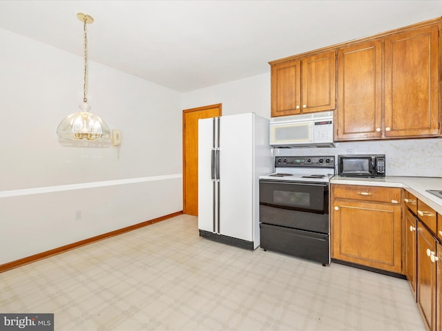 kitchen featuring decorative light fixtures, brown cabinets, light countertops, light floors, and white appliances
