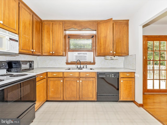 kitchen featuring brown cabinets, a sink, white microwave, electric stove, and black dishwasher