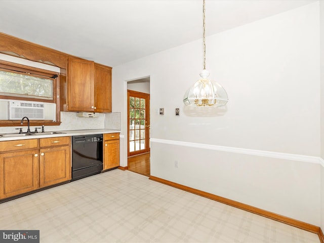 kitchen with brown cabinetry, light countertops, baseboards, a sink, and black dishwasher