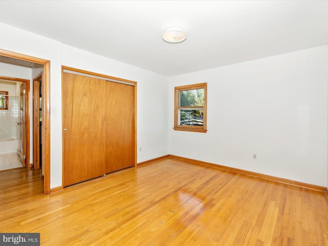 unfurnished bedroom featuring a closet, light wood-style flooring, and baseboards
