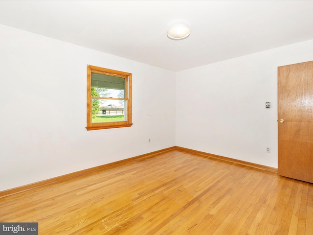 spare room featuring baseboards and light wood-type flooring