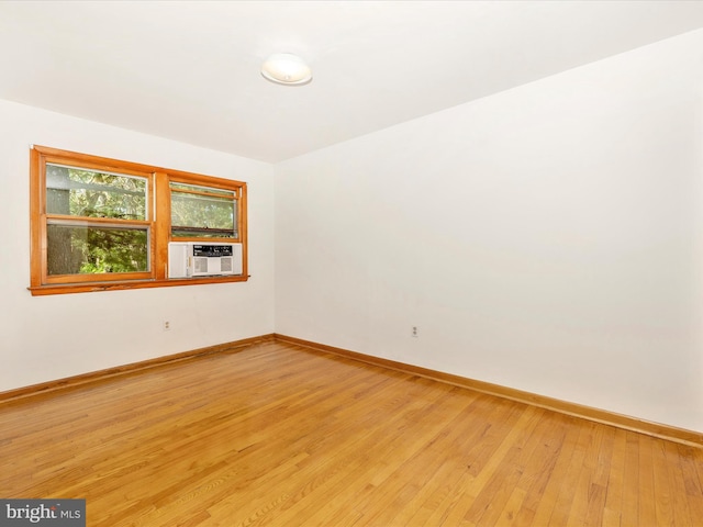 unfurnished room featuring baseboards, light wood-style floors, and cooling unit