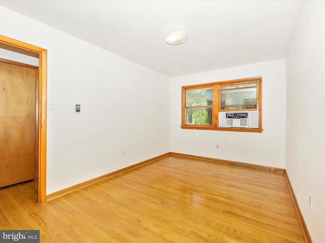 empty room with baseboards, cooling unit, and light wood-type flooring