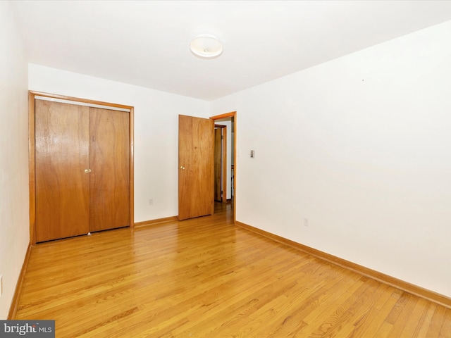 unfurnished bedroom featuring baseboards, a closet, and light wood-type flooring