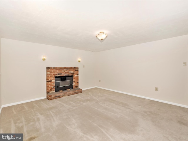 unfurnished living room with baseboards, a brick fireplace, and light colored carpet