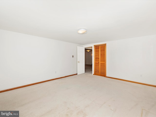 empty room with baseboards and light carpet