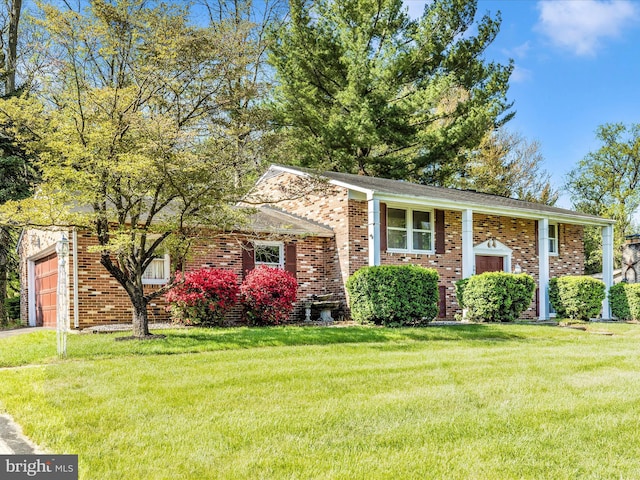 split foyer home featuring brick siding, a front yard, and a garage