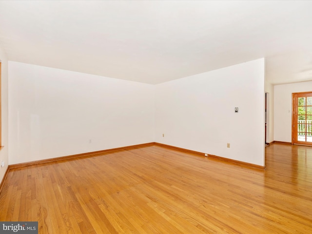 empty room with baseboards and light wood-style flooring