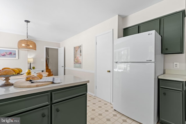 kitchen with freestanding refrigerator, light floors, light countertops, green cabinets, and decorative light fixtures