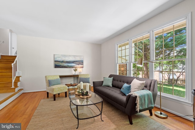 living room with baseboards, wood finished floors, and stairway