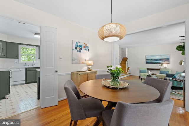 dining space with baseboards, light wood finished floors, and stairway