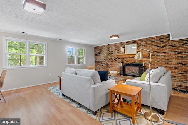 living area with baseboards, a textured ceiling, a brick fireplace, and wood finished floors