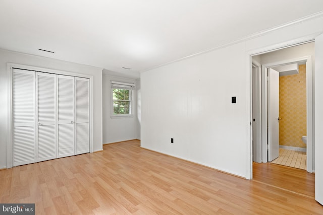 unfurnished bedroom with baseboards, light wood finished floors, and a closet