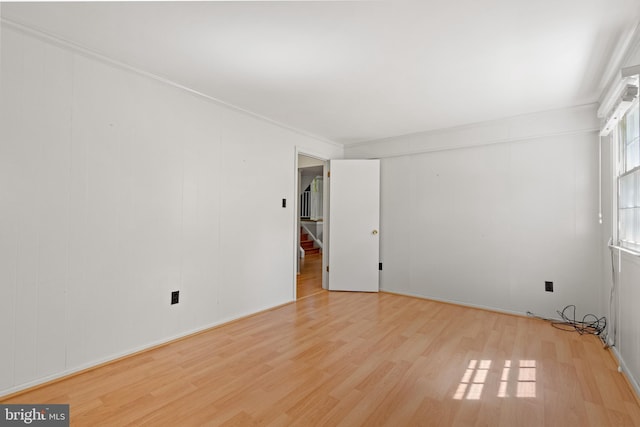 spare room featuring stairs, ornamental molding, and wood finished floors