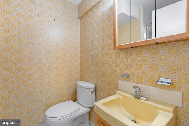 bathroom with a sink, tile walls, decorative backsplash, and toilet