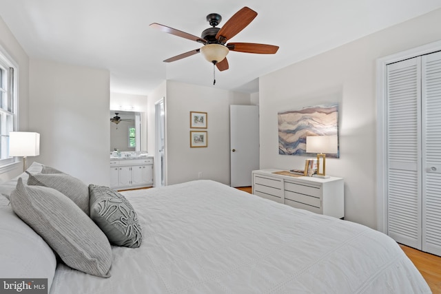 bedroom with ceiling fan, multiple windows, ensuite bath, and wood finished floors