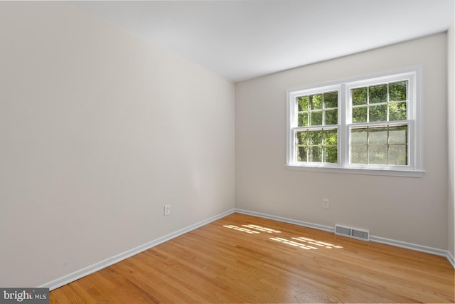 spare room featuring baseboards, light wood-style flooring, and visible vents