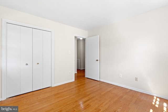 unfurnished bedroom with baseboards, a closet, and light wood finished floors