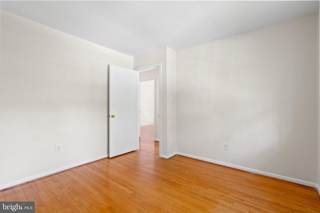 empty room featuring baseboards and light wood finished floors