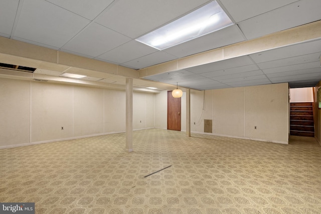 finished basement with baseboards, stairs, and a paneled ceiling