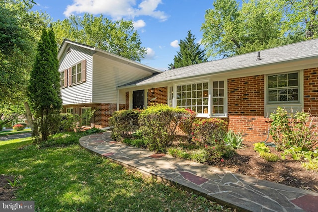 tri-level home featuring a front lawn and brick siding