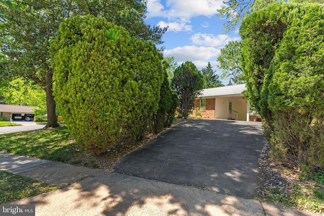 view of side of home with an attached carport, brick siding, and aphalt driveway