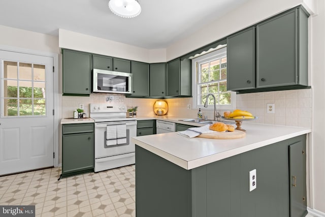 kitchen with a peninsula, light floors, green cabinetry, and white appliances