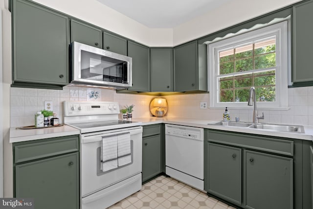 kitchen with white appliances, light countertops, a sink, and green cabinets